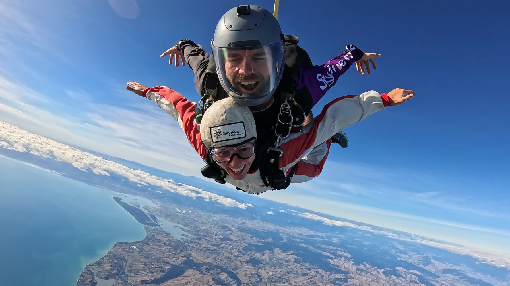 smiling skydivers freefalling over beach