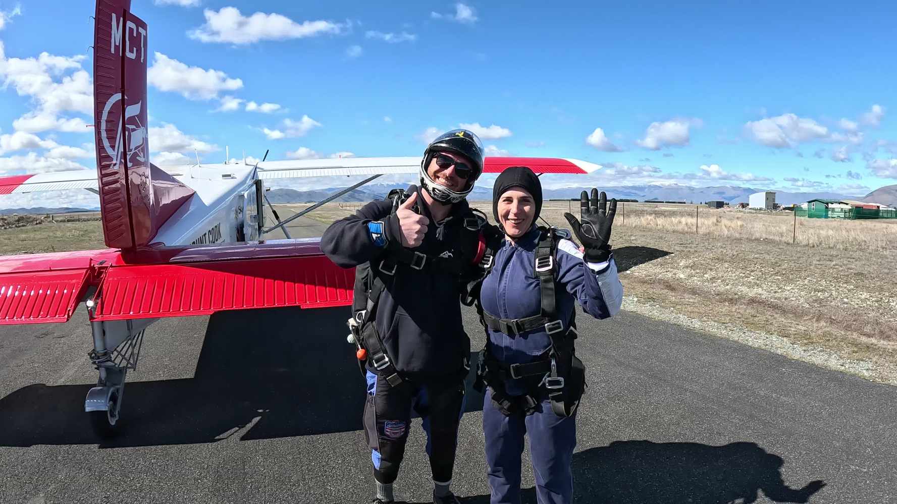 Plane with skydiver in jumpsuit in front of mountains 