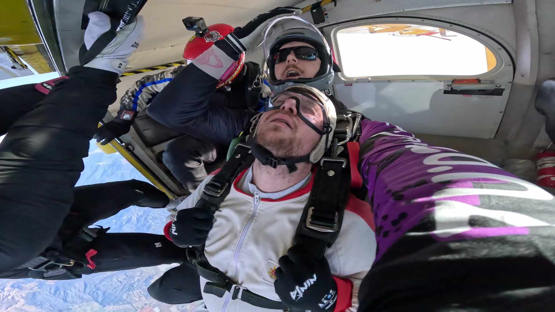 Tandem skydivers in plane with eyes closed